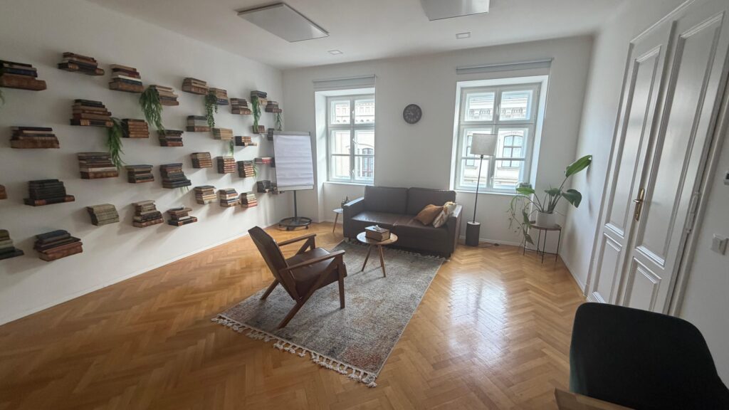 Heller Praxisraum mit Sofa, Sessel und Bücherwand in der Bösendorferstraße in Wien